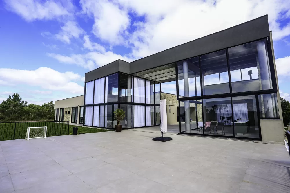 Engenheiro negro com capacete branco e colete de segurança analisando documentos em uma prancheta.